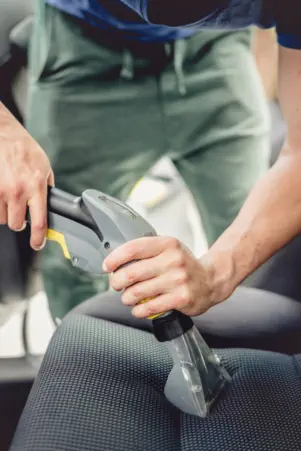 Vacuuming the inside passenger seat of a car